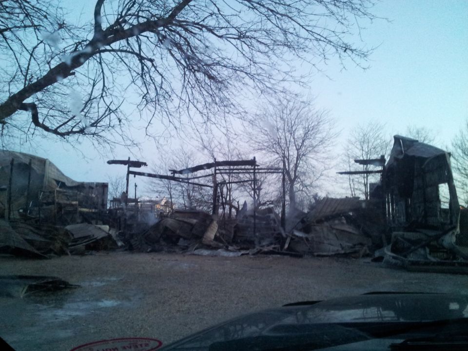 Ruined structures after a fire, with debris and bare trees.