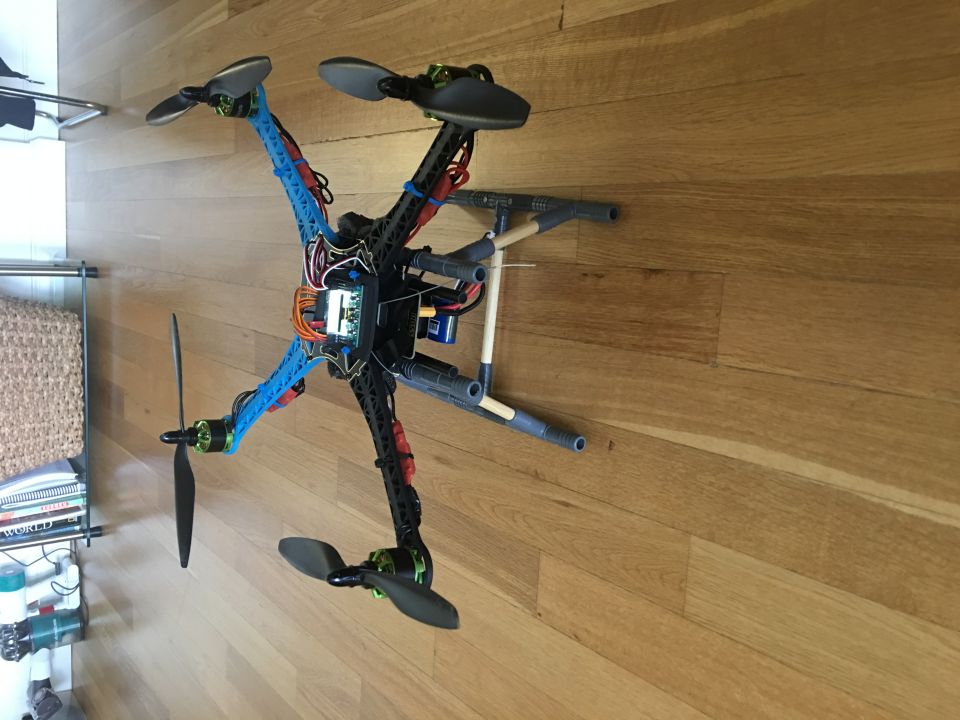 Custom hexacopter drone with blue and black arms on a wooden floor.