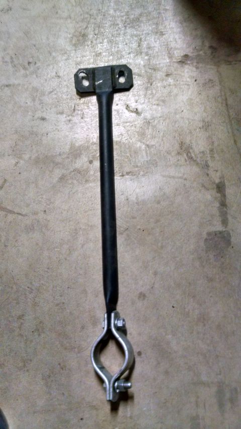 1985 Jeep CJ7 - A black metal bracket with a clamp attached to the bottom is shown against a concrete surface. The bracket has two holes at the top for mou…