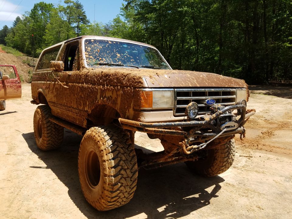 Mud-covered 1988 Ford Bronco with large tires and winch