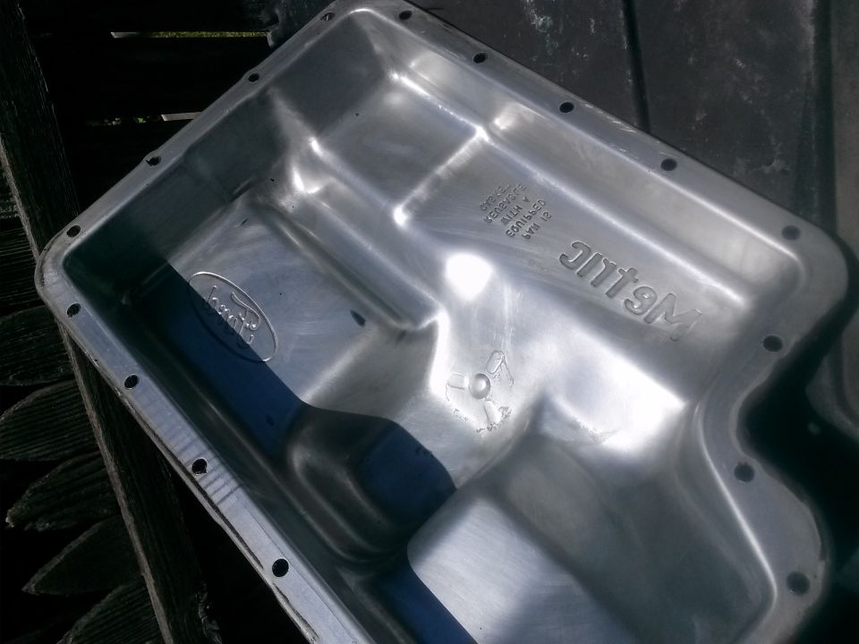 Shiny aluminum Ford oil pan with embossed text.