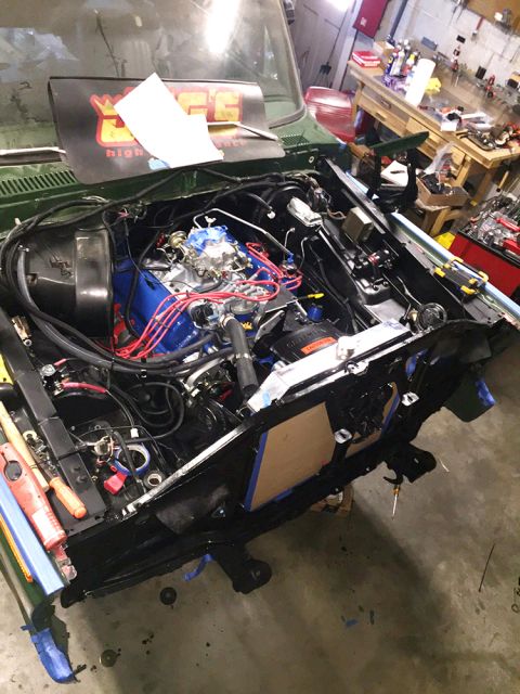 1978 Ford Bronco - The engine bay of a classic Ford Bronco is shown with the hood open, revealing a blue engine block, red spark plug wires, and a carburetor.…