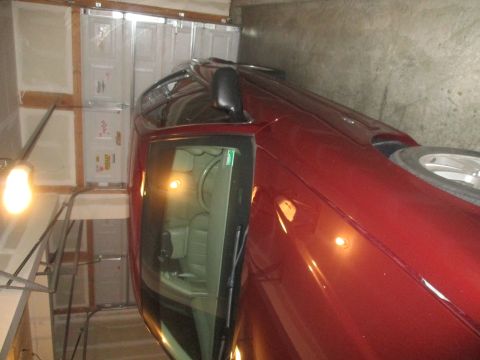 2004 Ford Crown Victoria - A red sedan is parked in a garage, angled towards the right side of the frame. The vehicle's interior, including the dashboard and seats, i…