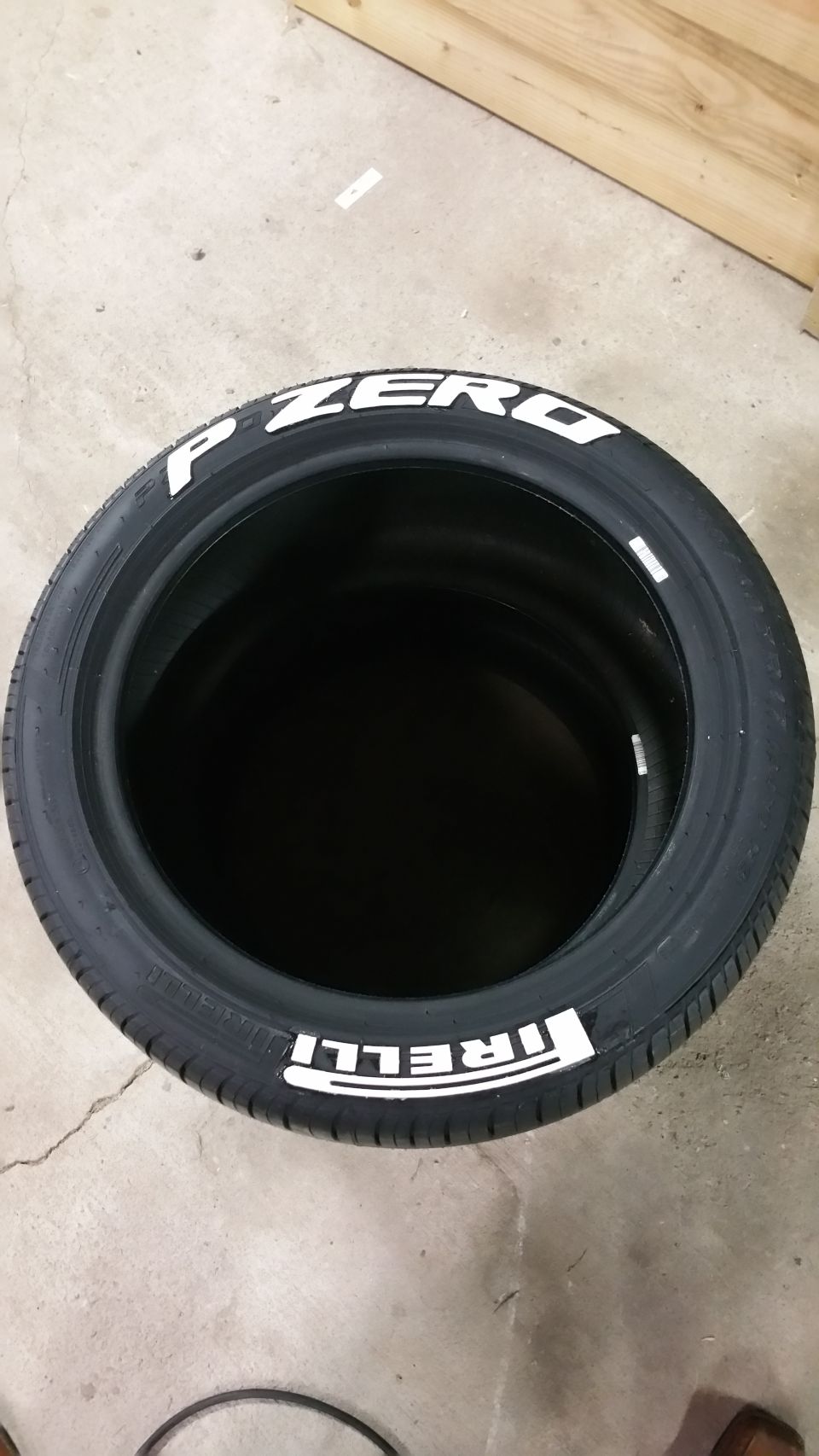 Black Pirelli P Zero tire with white lettering, viewed from above.