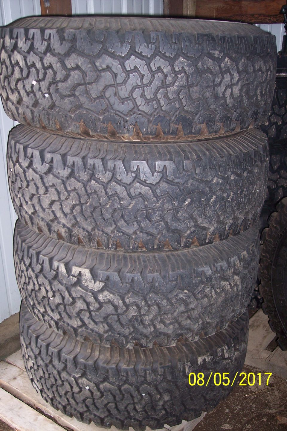 Stack of four off-road tires with aggressive tread pattern.