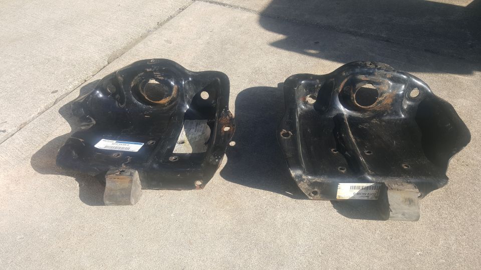 Two black metal vehicle brackets on concrete, one with a partial sticker.