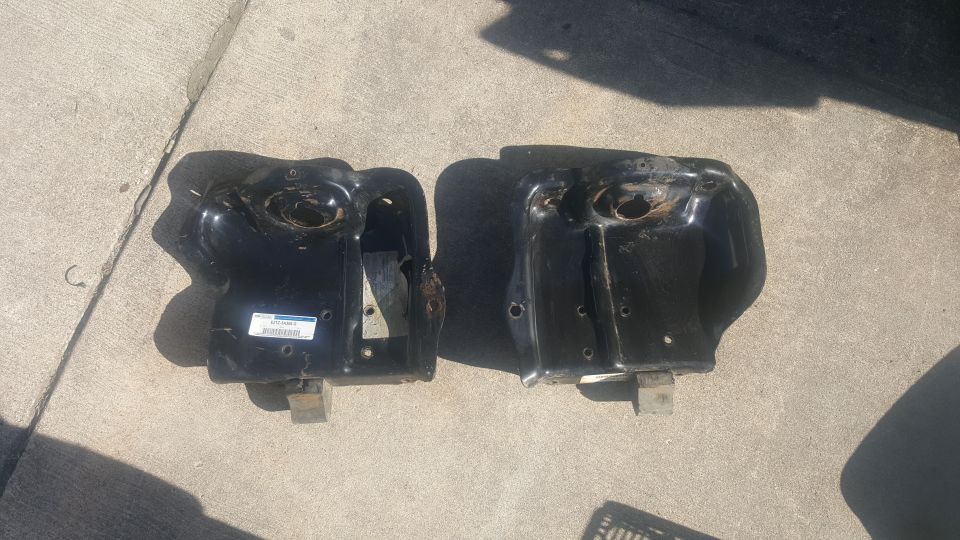 Two black metal vehicle brackets on concrete, one with a label.
