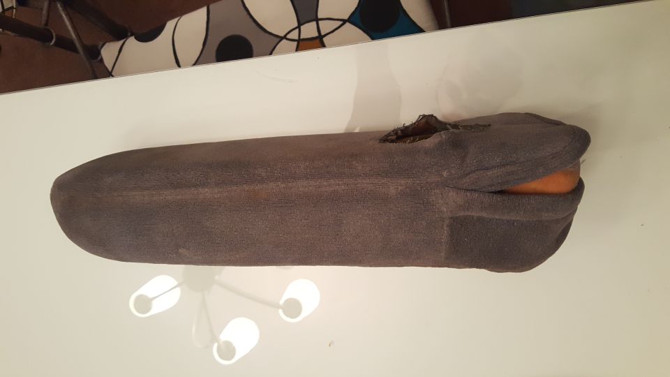 A sock covering an orange object on a white table.
