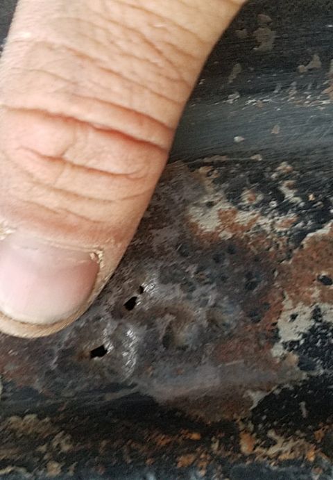1988 Ford Bronco - A close-up shows a person's thumb next to a rusted metal surface with several small holes. The metal appears to be part of a vehicle body,…