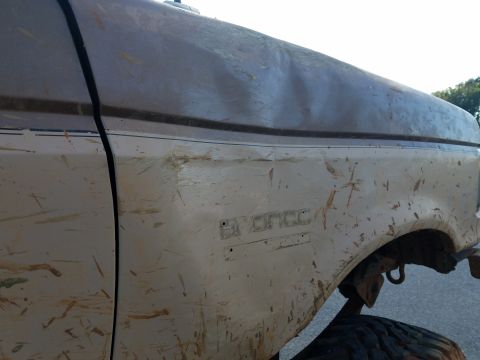 1988 Ford Bronco - The side panel of a mud-splattered Ford Bronco shows the model name embossed on the fender.