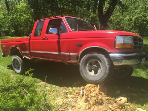 1996 Ford F-150 - This red 1995 Ford F-150 pickup truck shows significant rust and body damage on its rear fender and rocker panel.