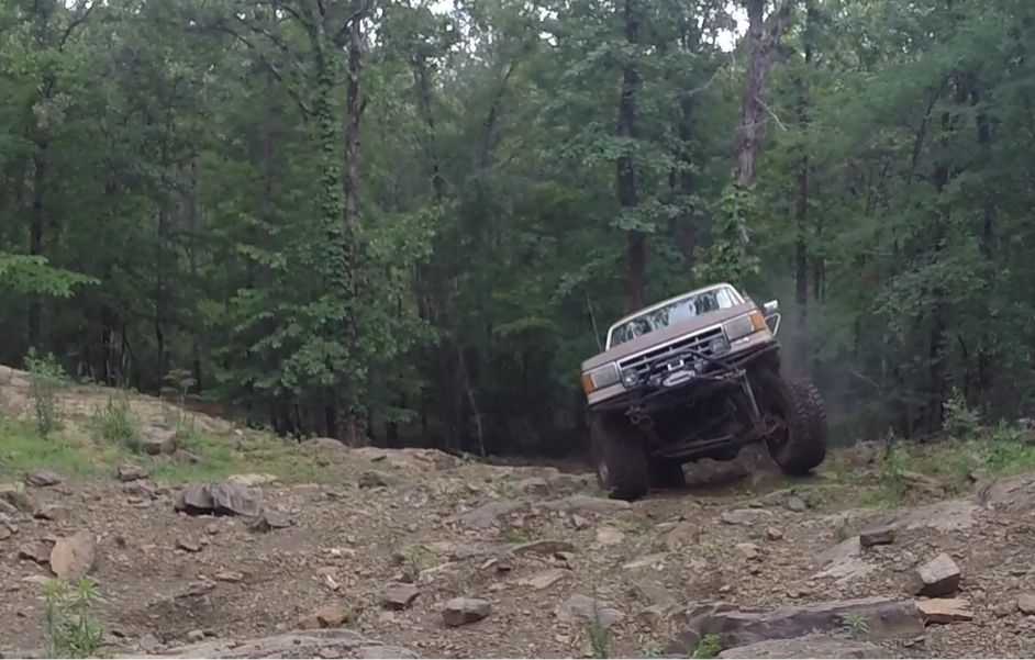 Brown off-road SUV climbing rocky terrain, front view