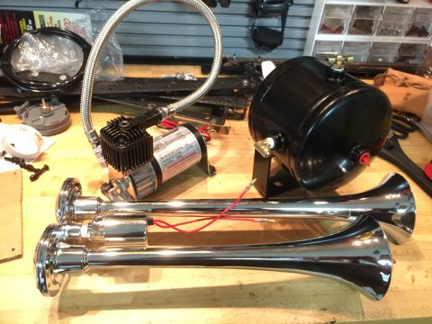 1996 Ford Bronco - A kit for installing air horns, including a compressor, tank, and horns, is laid out on a workbench.