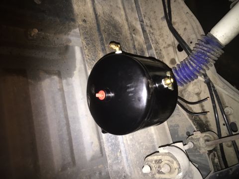 1996 Ford Bronco - Underside view of a black air tank with brass fittings and a red cap.