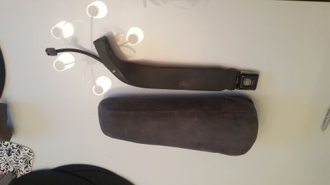 1995 Ford Bronco - A dark-colored seat belt and a padded armrest are displayed on a white surface.