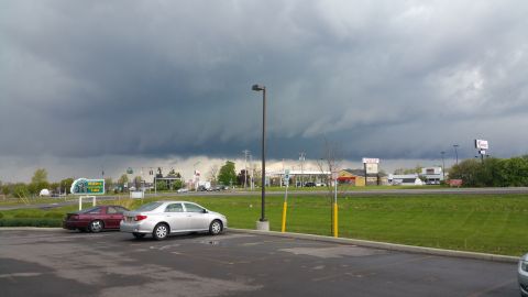 2006 Mitsubishi Evolution - Two cars are parked in a lot as dark storm clouds gather overhead.