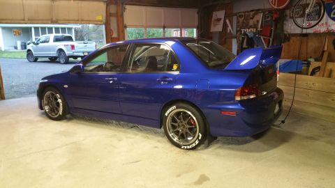 2006 Mitsubishi Evolution - A blue 2006 Mitsubishi Lancer Evolution is parked in a garage, with a white pickup truck visible outside.