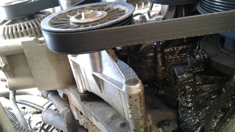 1996 Ford F-350 - Close-up of engine belt and pulleys, showing oil accumulation on parts.