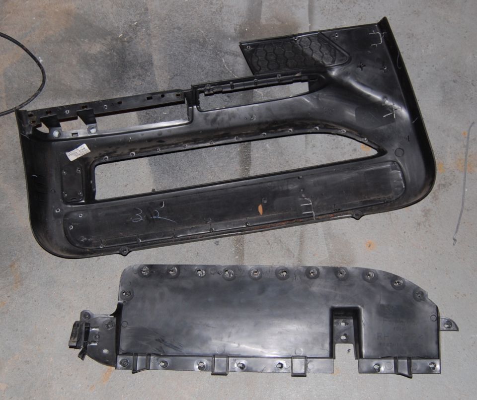 Two black plastic car door panels, one large and one smaller, lying on a concrete floor
