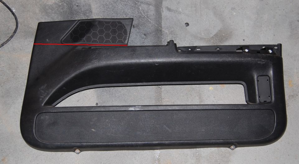 Black car door panel with a hexagonal speaker grille and a red line above it