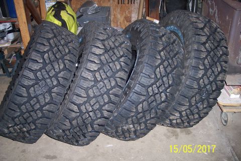 1995 Ford Bronco - Four off-road tires are shown leaning against a wall in what appears to be a garage or storage area.