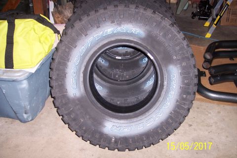 1995 Ford Bronco - A stack of Goodyear Wrangler tires are visible, with a yellow bag and some exhaust pipes in the background.