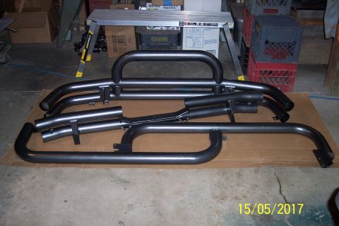 1995 Ford Bronco - Two black steel off-road bumpers are displayed on cardboard in a garage setting.
