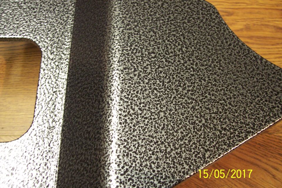 Metal part with speckled silver and black finish, showing a cutout and a raised section