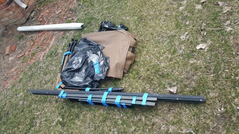 1995 Ford Bronco - Disassembled tent components are laid out on the grass, secured with blue tape.