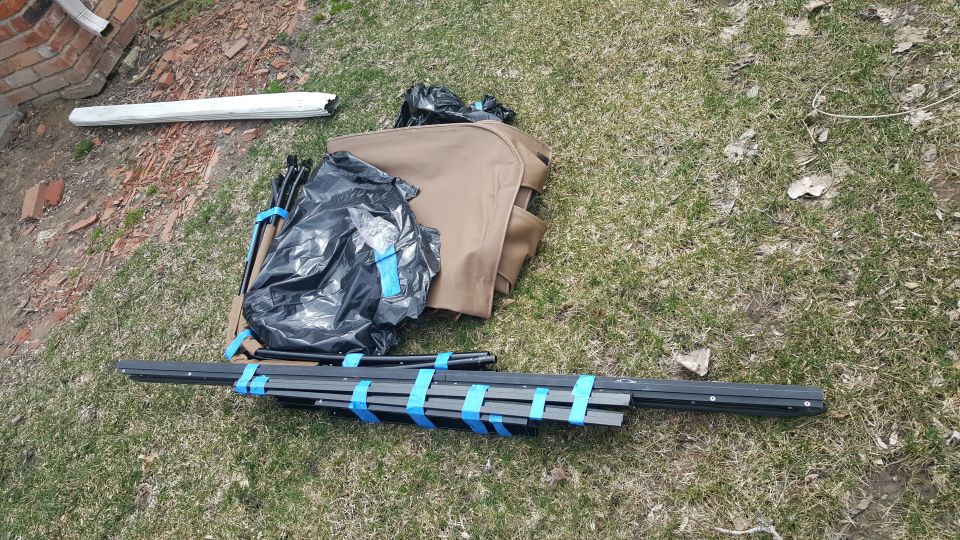 tent poles and fabric bundled with blue tape on grass