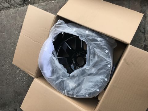1996 Ford Bronco - A black wheel is packaged in a cardboard box, with the Supermotors.net logo visible in the lower right corner.