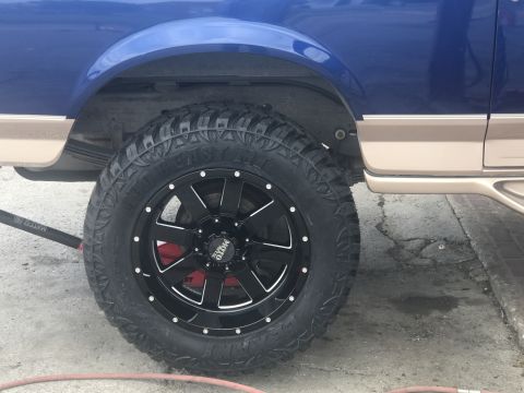 1996 Ford Bronco - Close-up of a wheel and tire on a blue and tan SUV.