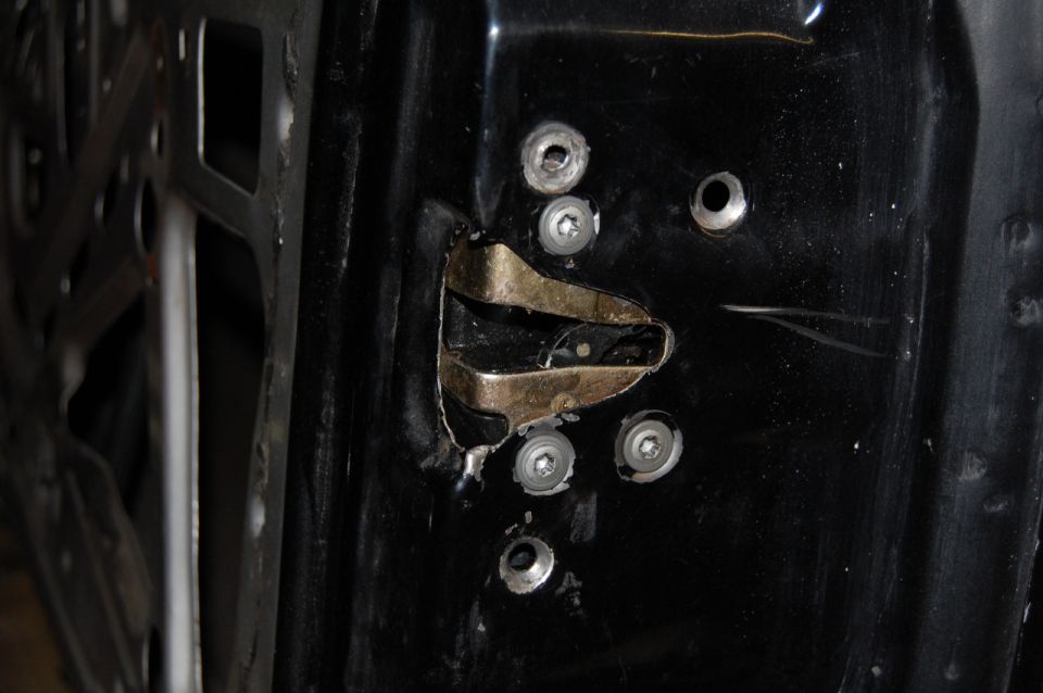 Close-up of a car's door latch mechanism with visible screws and metal components