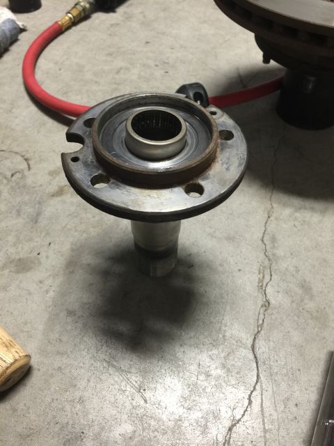 1996 Ford Bronco - A wheel hub assembly is shown on a concrete floor, with a red air hose and a brake rotor visible in the background.