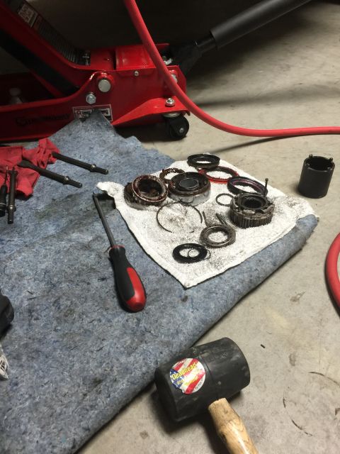 1996 Ford Bronco - Various disassembled vehicle components, including gears and bearings, are laid out on a mat with tools nearby, suggesting a repair or main…