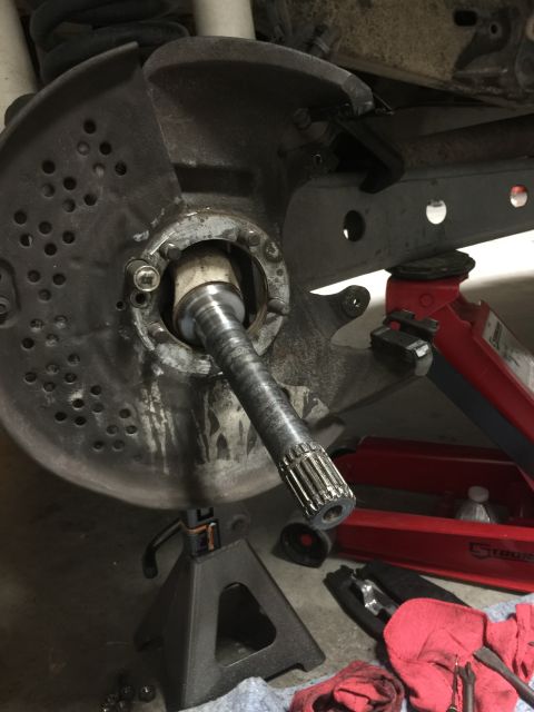 1996 Ford Bronco - Front wheel hub assembly disassembled, showing axle shaft and brake components. Supported by jack stands.