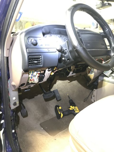 1996 Ford Bronco - The interior of a 1996 Ford Bronco shows the dashboard, steering wheel, and exposed fuse box, with a cordless drill on the floor.