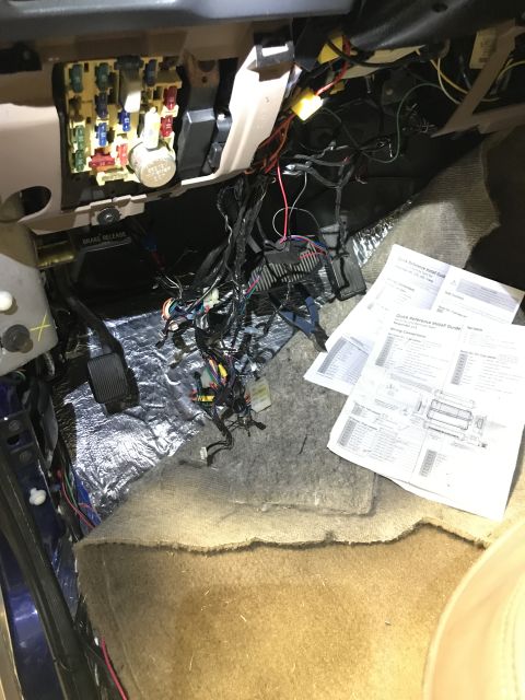 1996 Ford Bronco - A complex web of wires and a fuse box are visible inside a vehicle's interior, alongside technical documents.