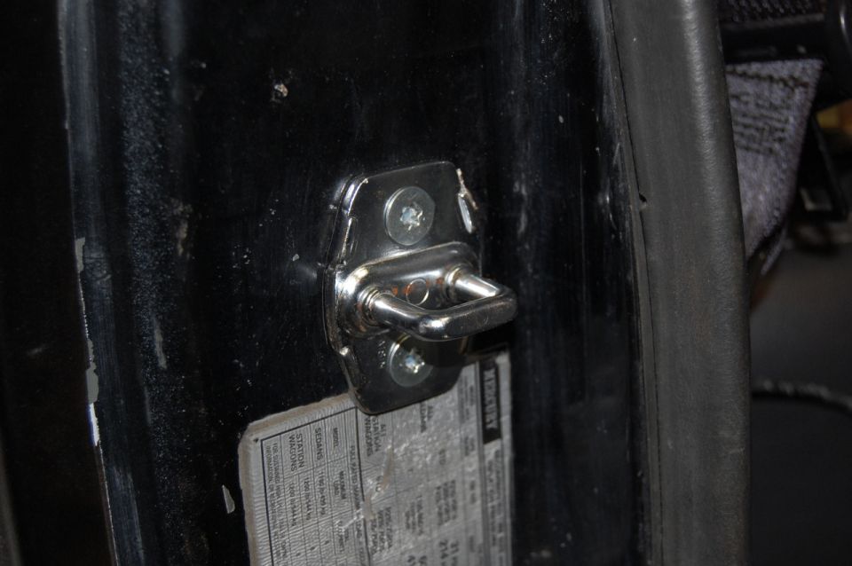 Door latch mechanism on black interior panel with visible text label