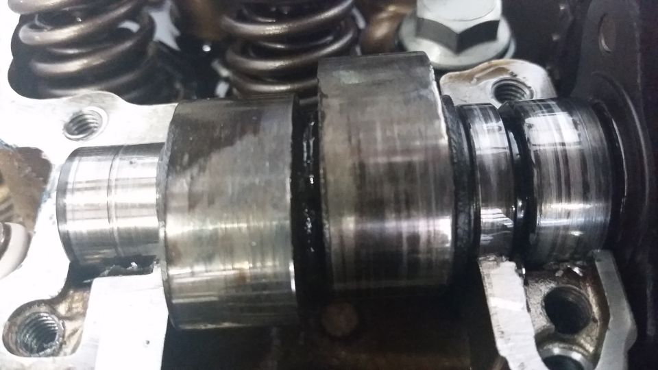 Close-up of a worn camshaft with valve springs visible above