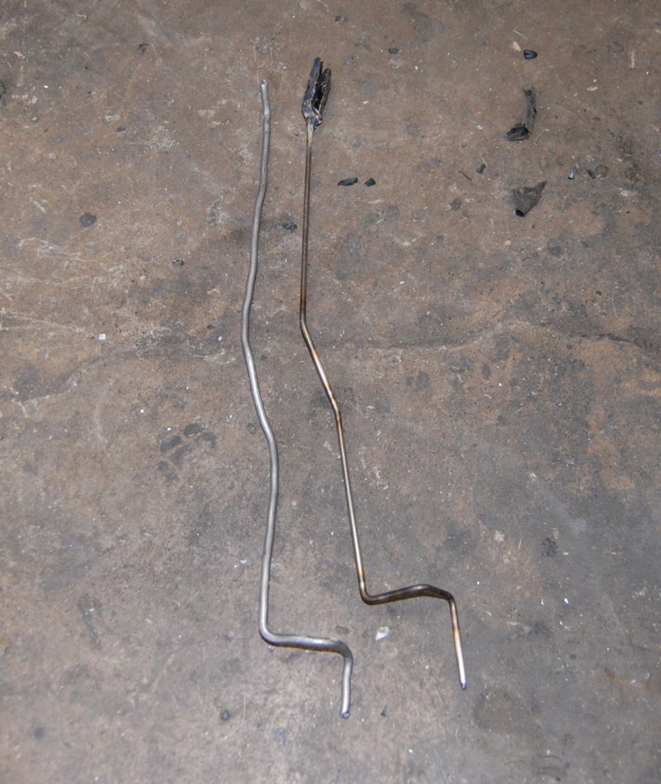Two metal rods, one silver and one burnt, on a concrete floor