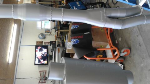 1985 Ford Bronco - An exhaust system is shown on a cart in a garage setting.