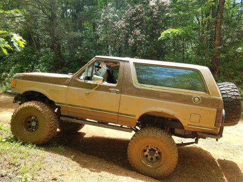 1988 Ford Bronco - This lifted 1988 Ford Bronco is equipped with large off-road tires, ready for adventure on a wooded trail.