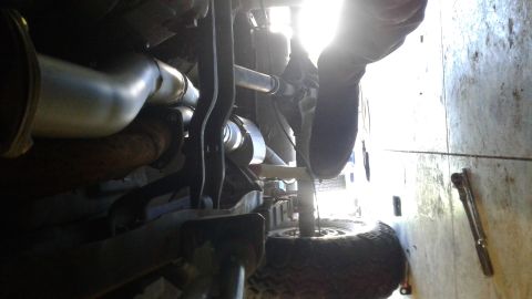 1985 Ford Bronco - Close-up view of the undercarriage, focusing on the exhaust pipes and suspension parts.