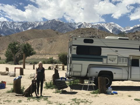 1997 Dodge 3500 - A woman and her dog are enjoying a scenic view next to a motorhome in a dry, mountainous area.