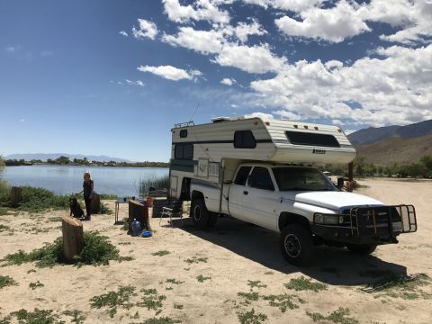1997 Dodge 3500 - White 1997 Dodge 3500 pickup truck with a camper shell parked near a lake with a person and dog.