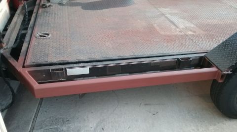 2016 Ford F-250 - Close-up view of a trailer deck, showing its diamond plate surface and red-painted frame.