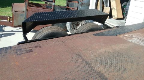 2016 Ford F-250 - A rusty truck cab sits behind a trailer deck with a black metal ramp.
