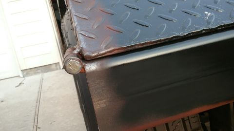 2016 Ford F-250 - Detail of a diamond plate toolbox hinge, showing the metal construction and a hex bolt.