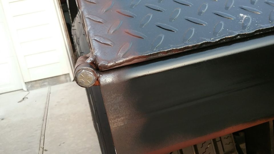 Close-up of a diamond plate toolbox hinge with a hex bolt